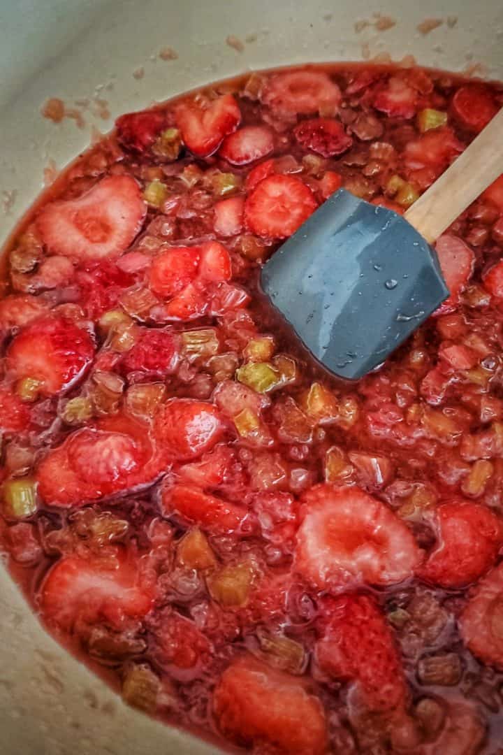 Whole fruit being broken down in pan being stirred