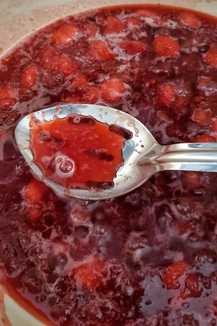 Spoon showing liquid from jam in pan