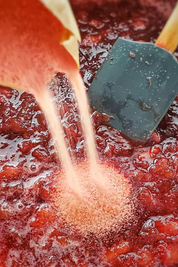 Strawberry gelatin being poured into jam mixture