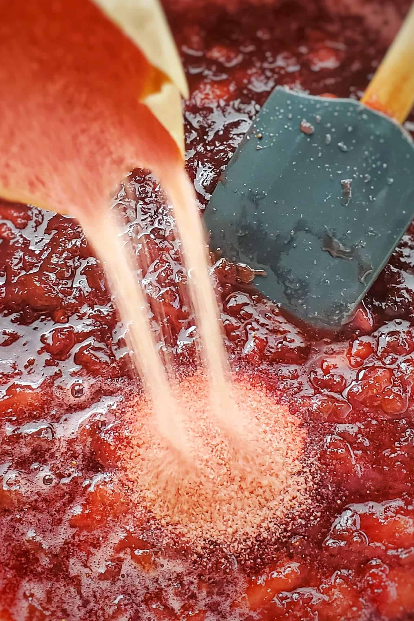 Strawberry gelatin being poured into jam mixture.