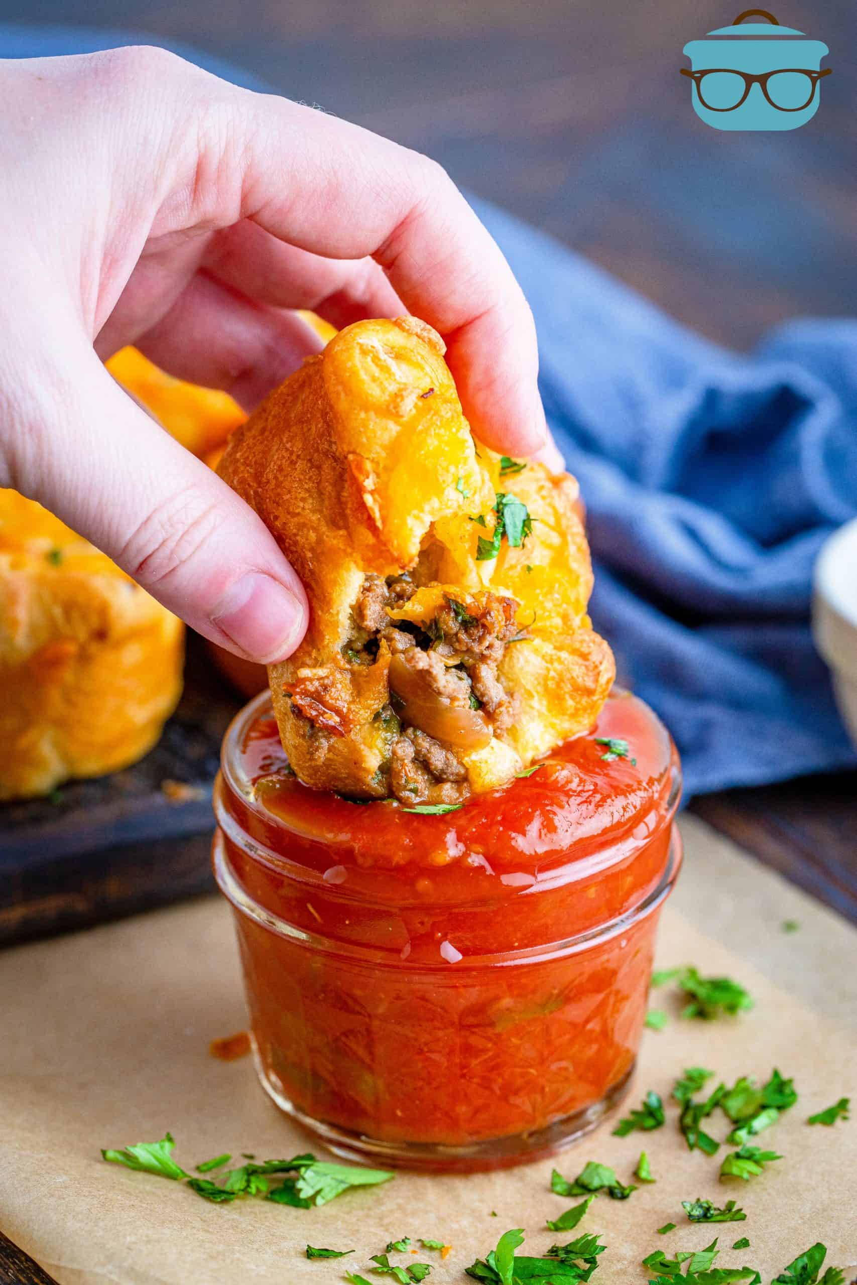 Hand dipping a Crescent Taco Cup in a jar of salsa.