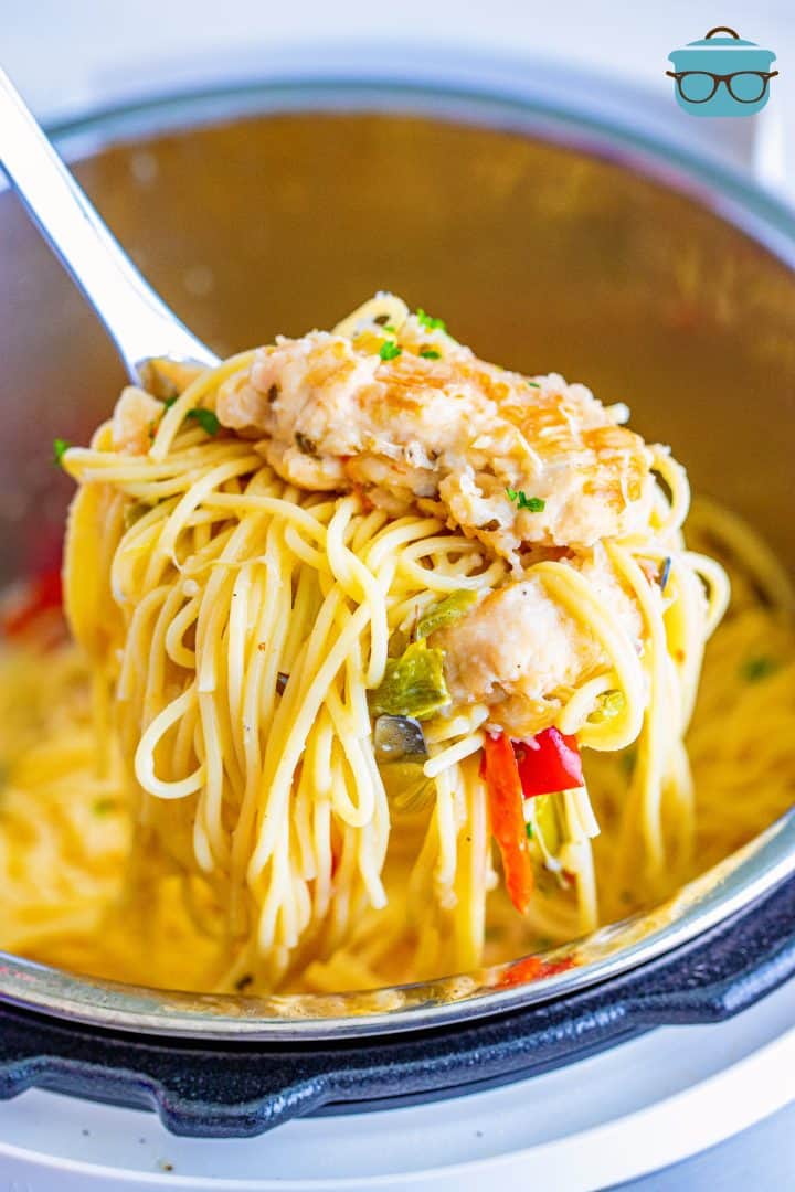 a silver spoon scooping out some chicken scampi from an instant pot.