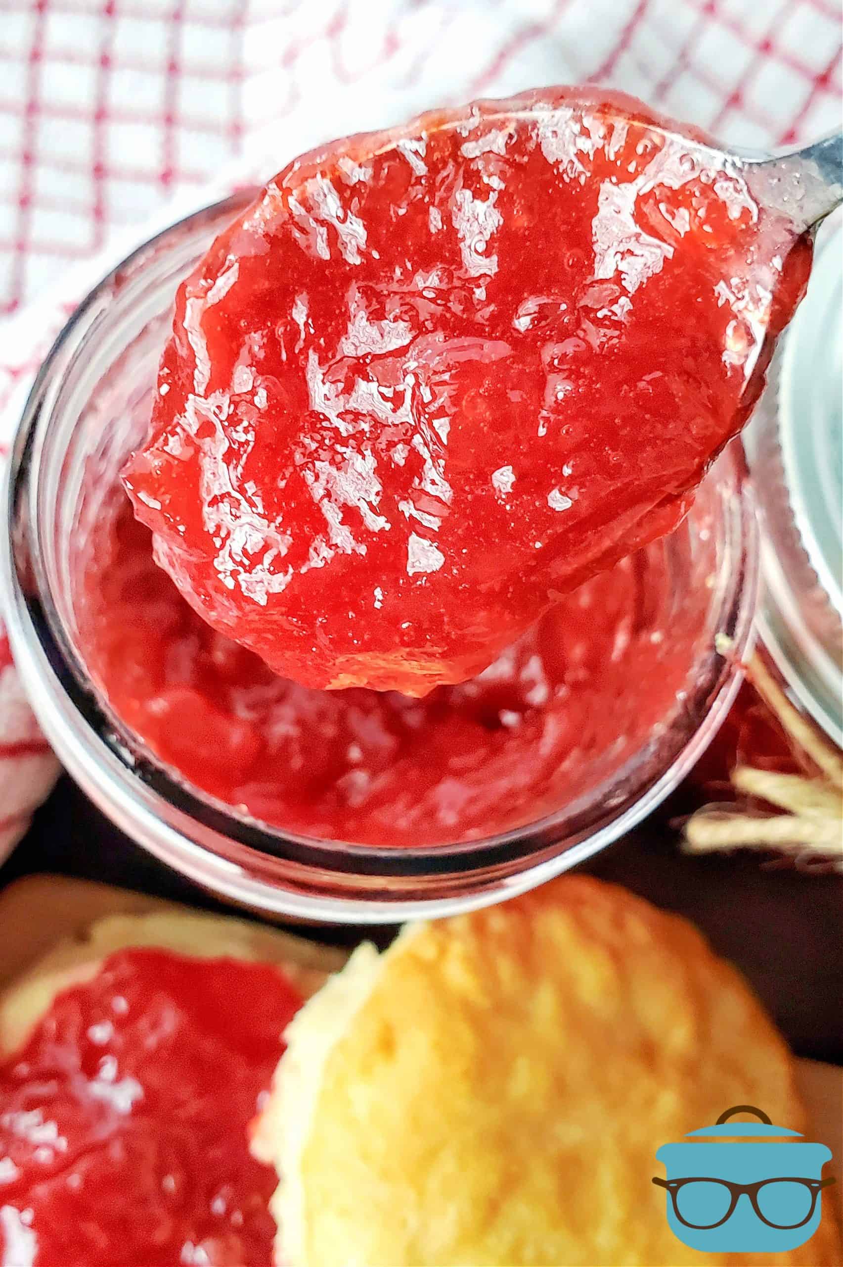 Overhead of jam on spoon over jar.