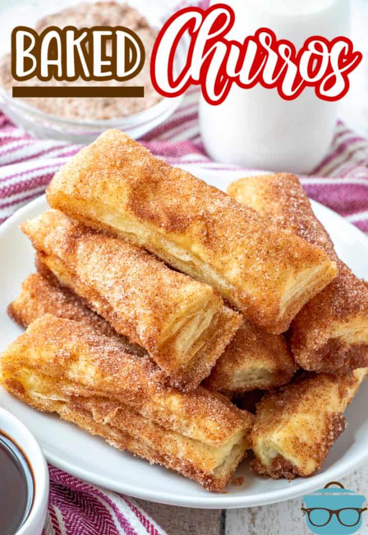 Easy Baked Churro recipe from The Country Cook, a stack of cinnamon sugar churros shown on a white round plate.