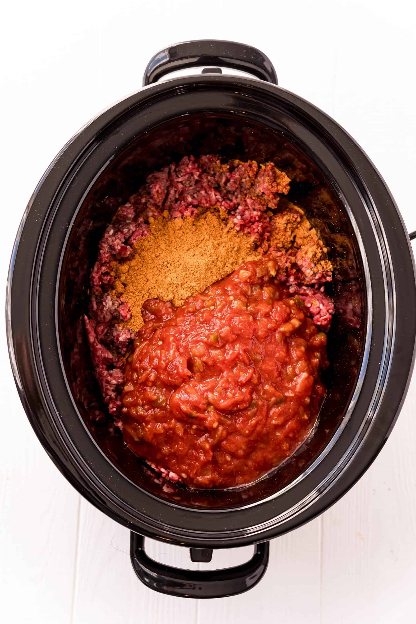 Salsa and taco seasoning added to black crock pot with ground beef