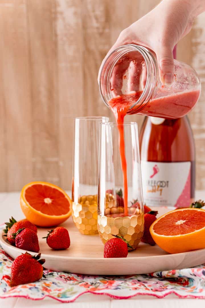 Strawberry and juice mixture being poured into serving glass.