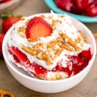 Square image of close up white bowl with Strawberry Pretzel Dessert in it