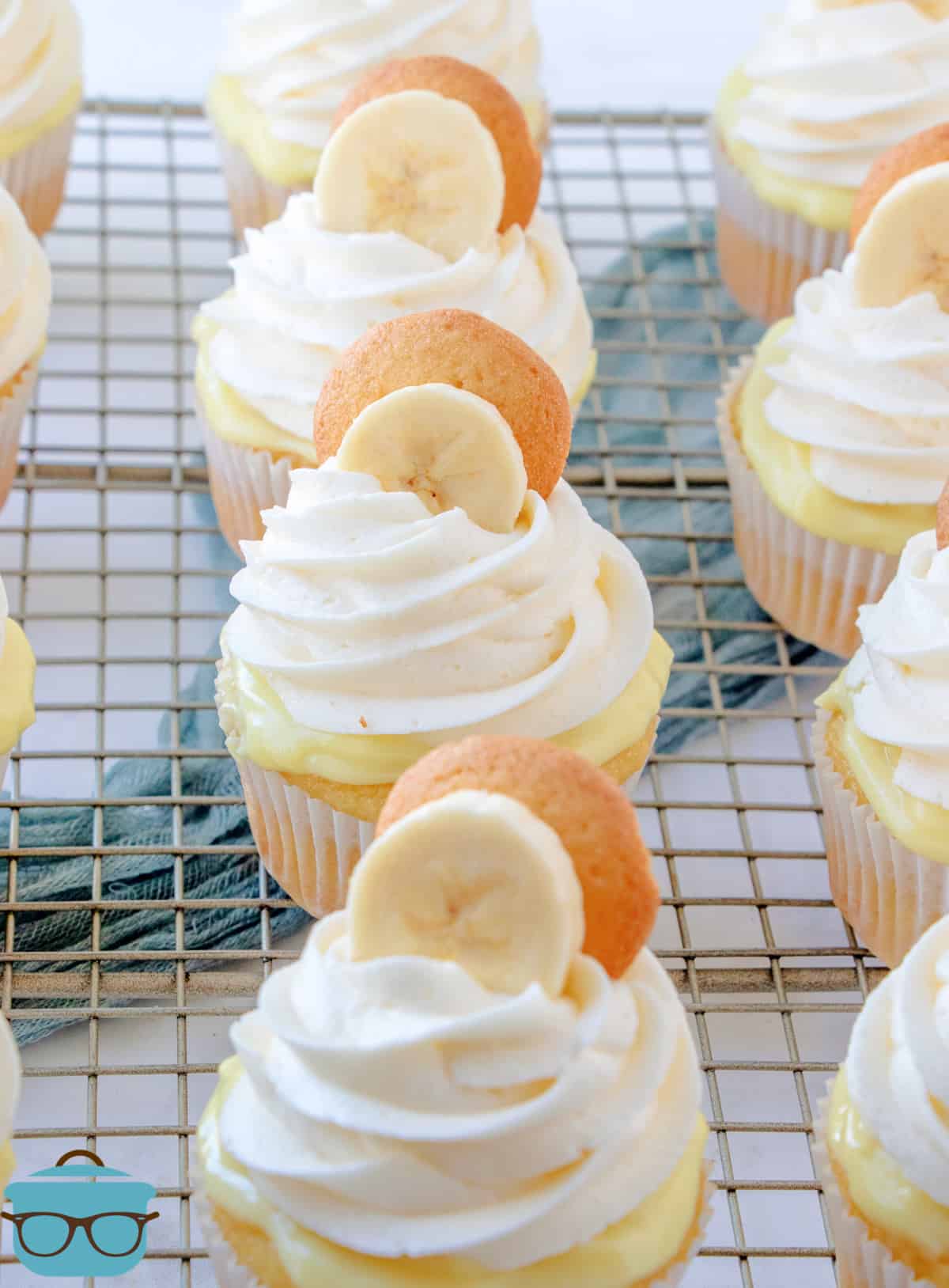 Finished frosted cupcakes topped with a banana slice and vanilla wafer on wire rack.