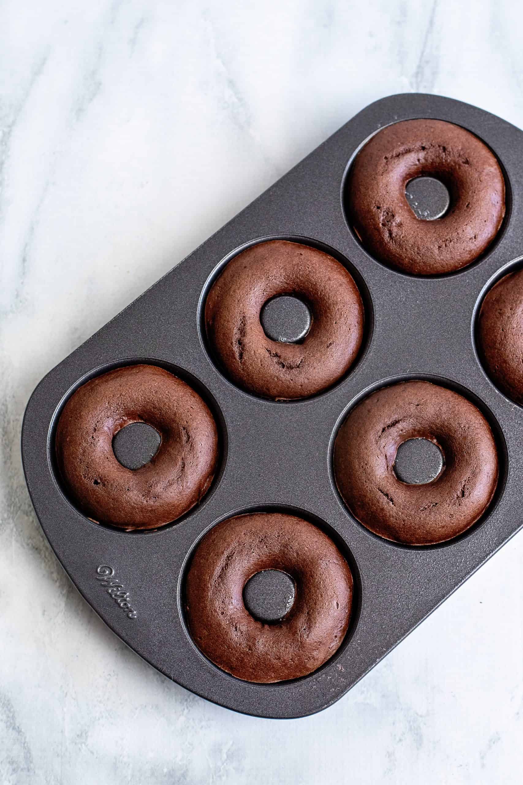 Baked donuts in donut pan overhead image