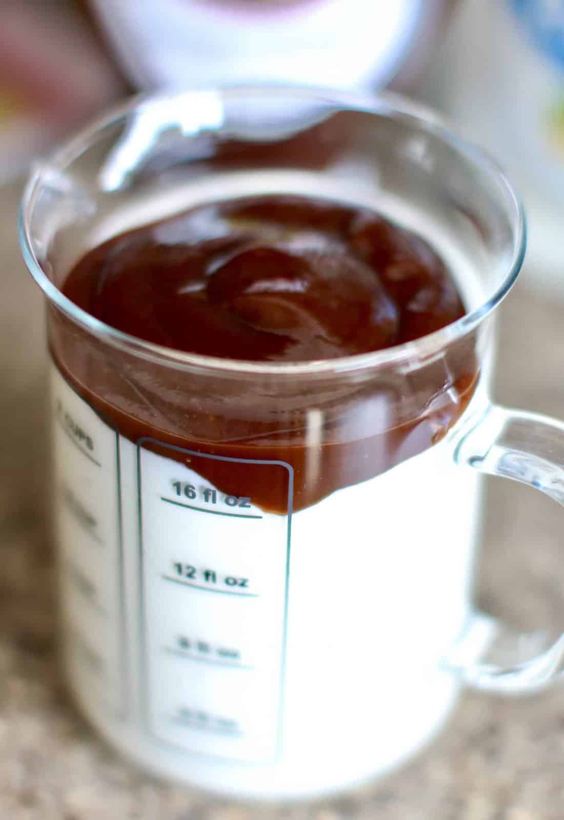 ranch dressing and barbecues sauce shown in a measuring cup beaker.