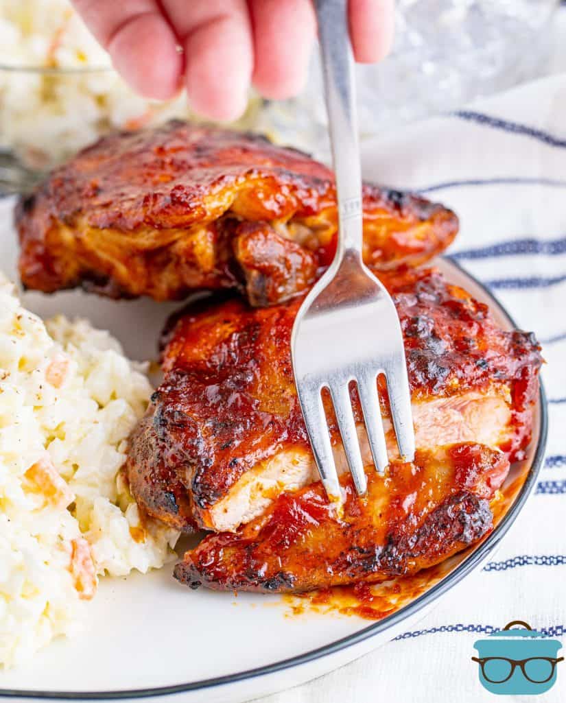 Plated Grilled BBQ Chicken Thighs on plate cut with fork going into cut portion