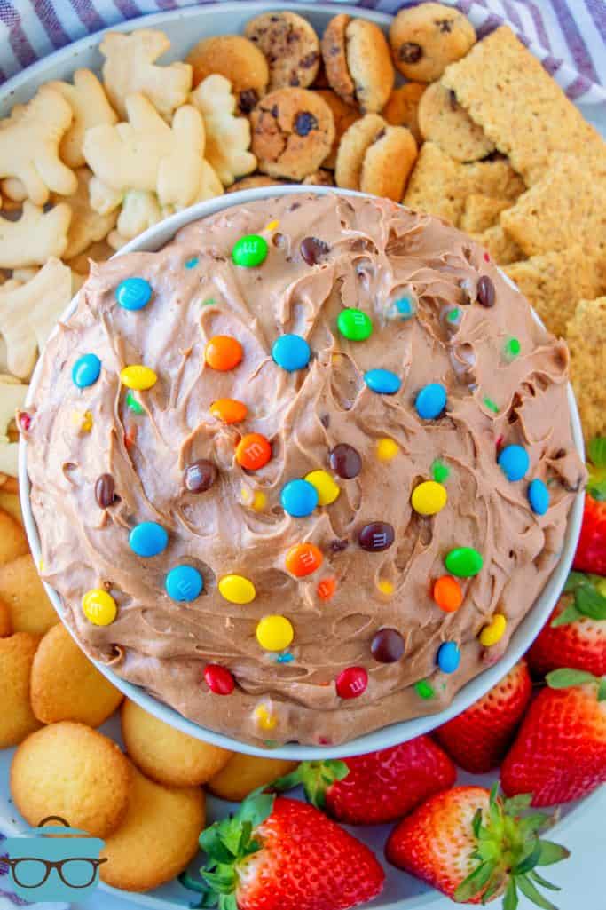 Overhead of M&M Brownie Batter Dip Recipe in bowl surrounded by fruit, cookies and crackers