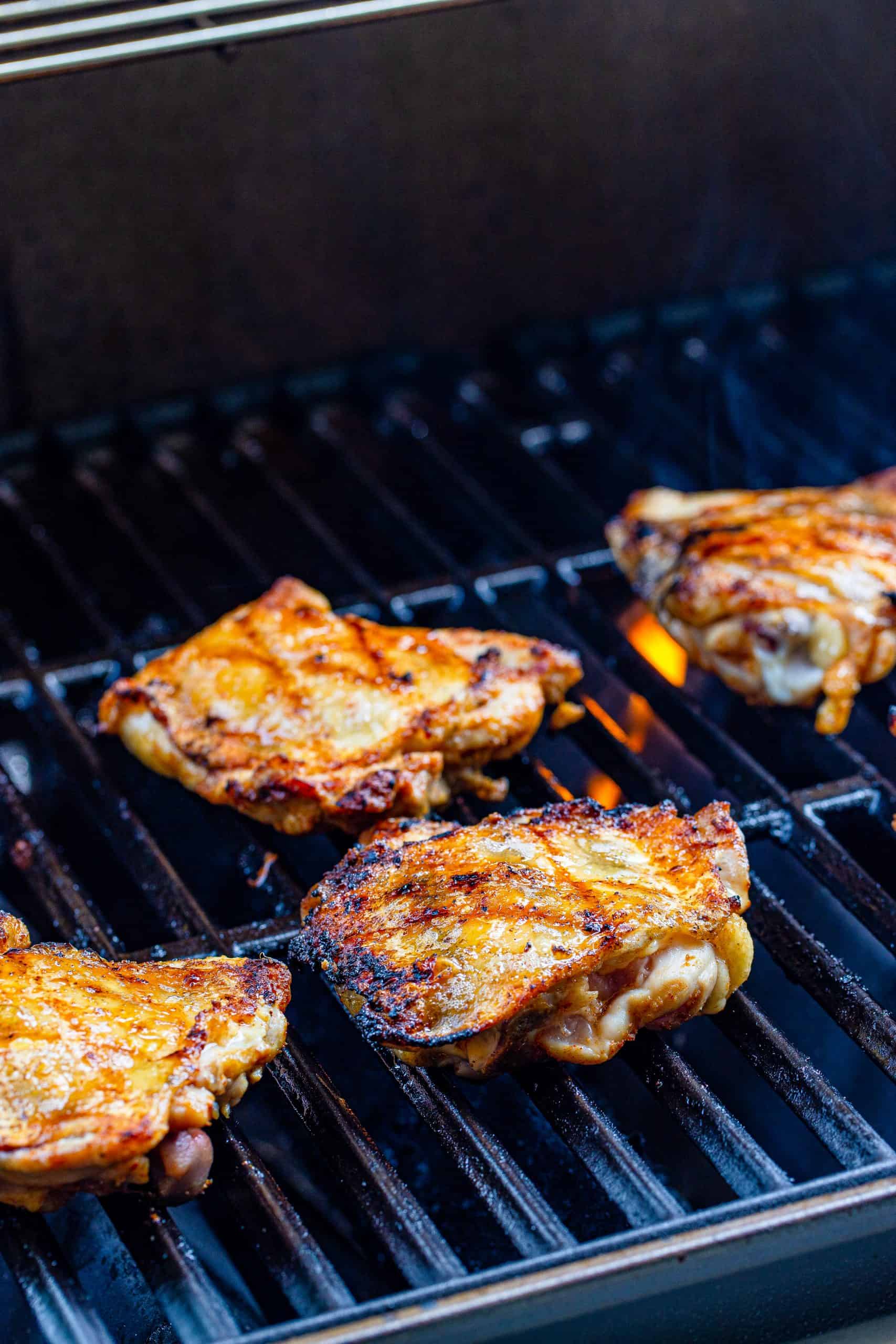 Chicken thighs getting brown on grill.
