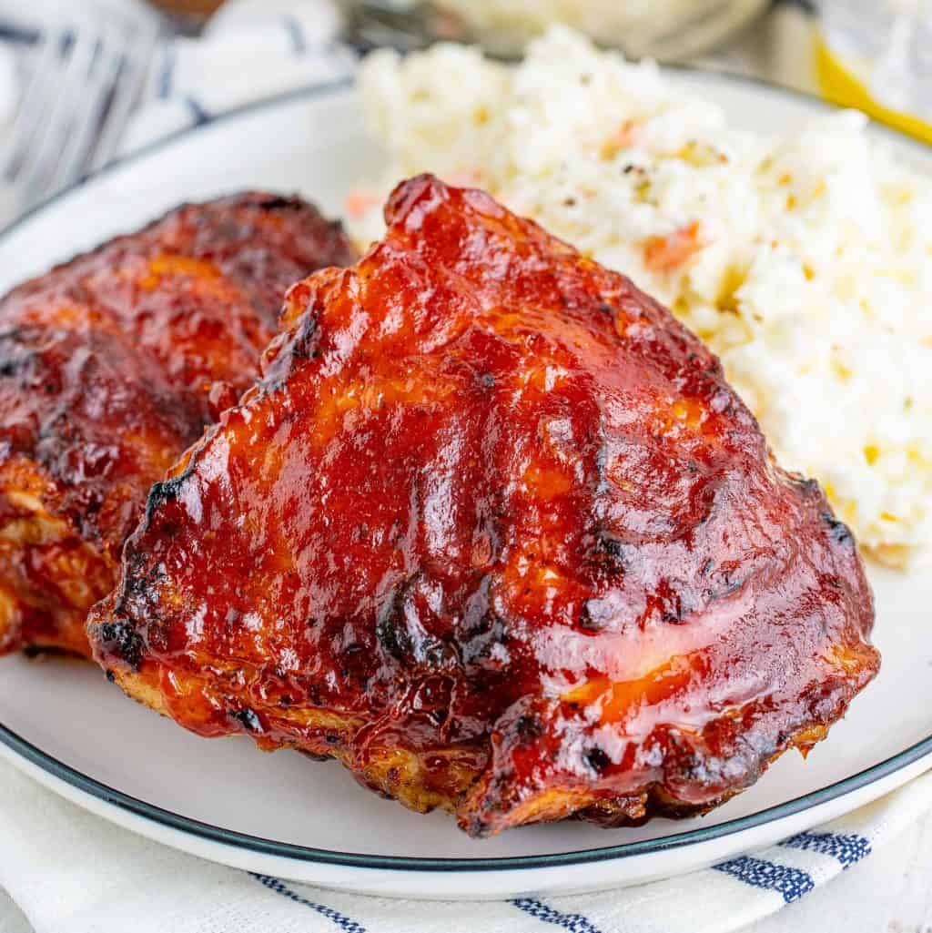 Close up of finished Grilled BBQ Chicken Thigh Recipe on plate with side dish square image