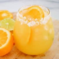 Close up square image of finished Margarita in glass with salt rim and orange slice