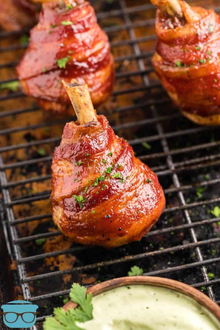 Finished Smoked Bacon Wrapped Chicken Lollipops on grill with dried cilantro
