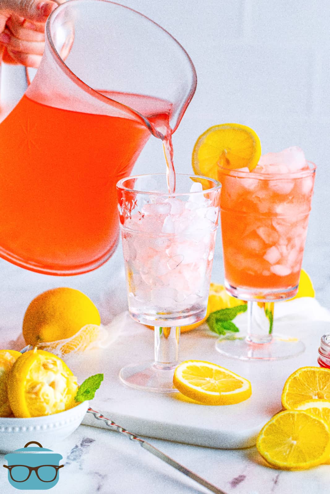 Pitcher pouring Homemade Pink Lemonade into glass with ice.