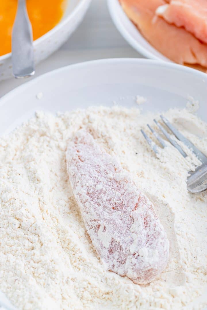 Chicken tender being dipped in flour
