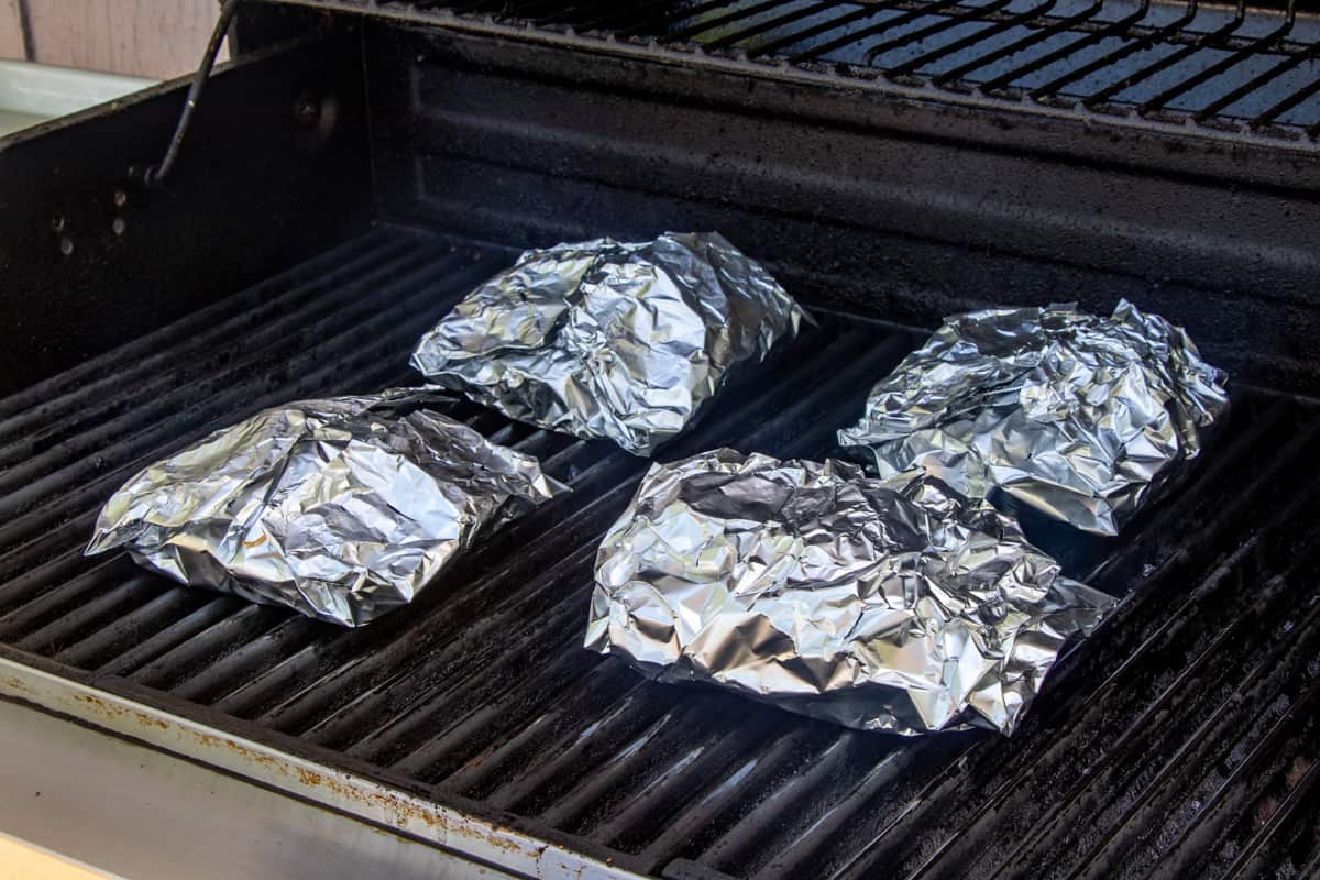four potato packets shown on grill.