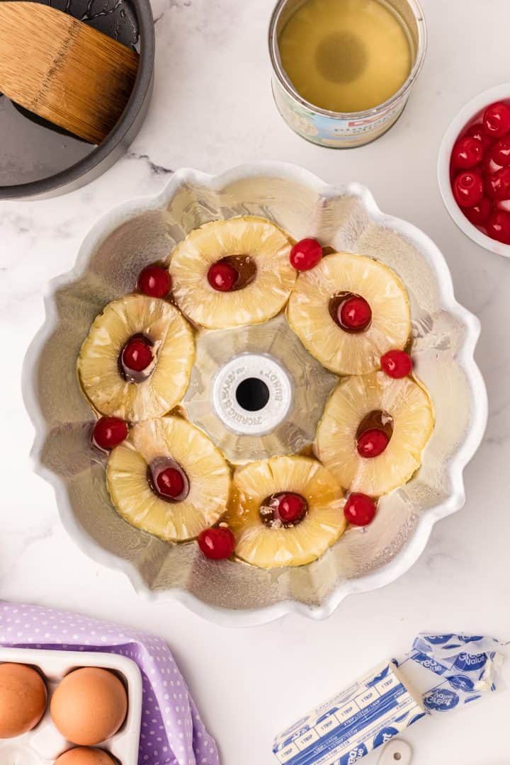 Pineapple rings and cherries arranged over brown sugar and butter in bundt pan
