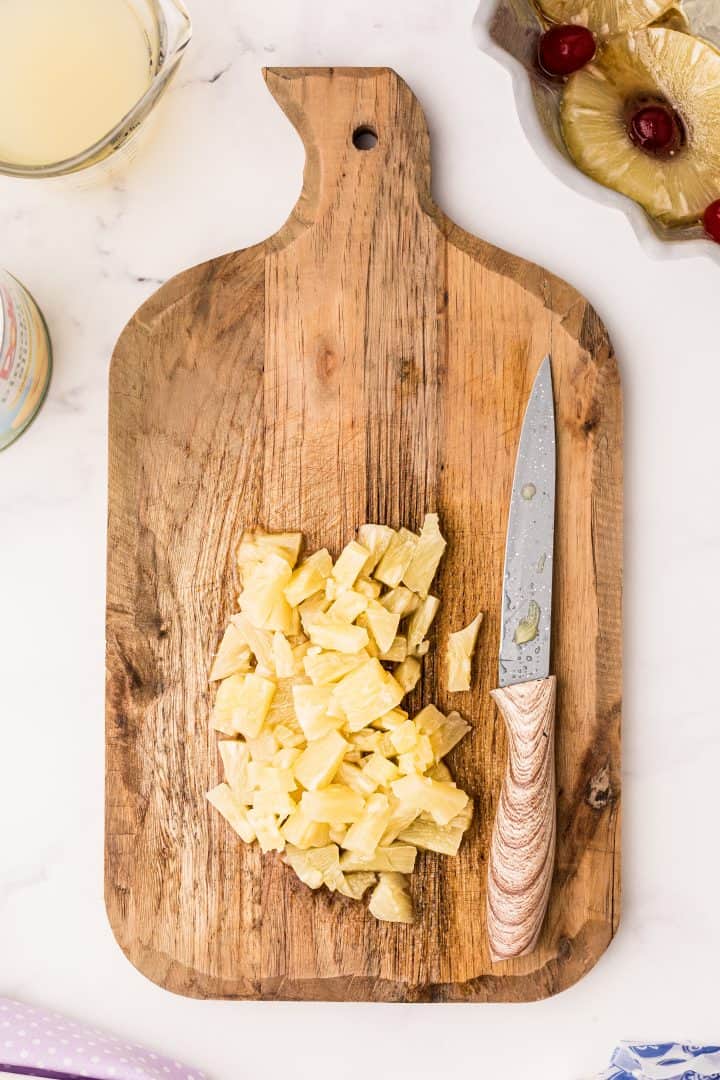 Chopped up pineapple rings on wooden cutting board