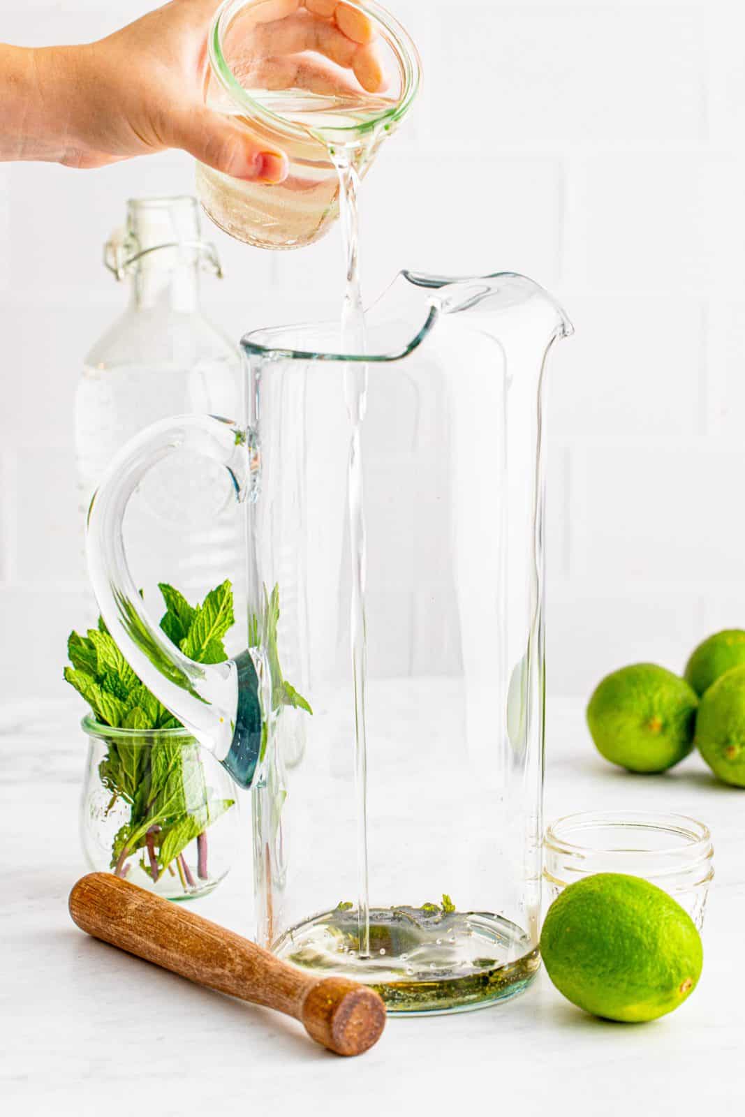 Simple syrup being cured into a tall glass pitcher.