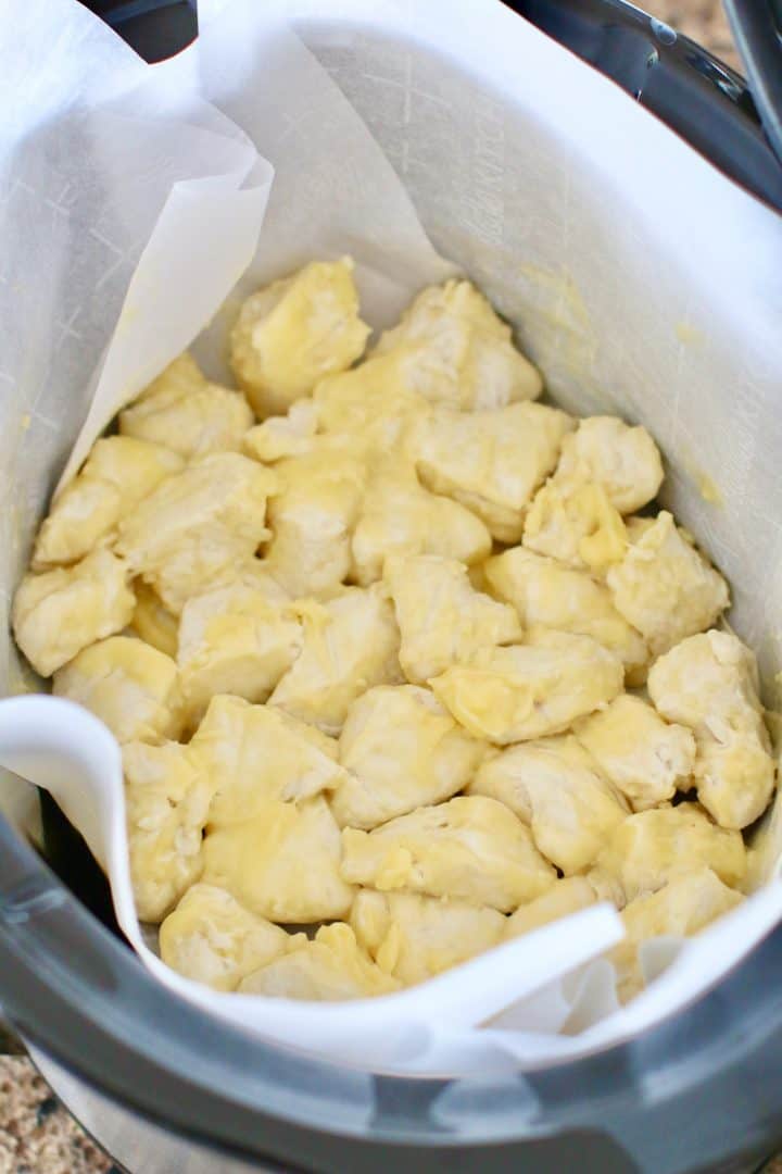 butter covered biscuit dough placed in a single layer in an oval crock pot