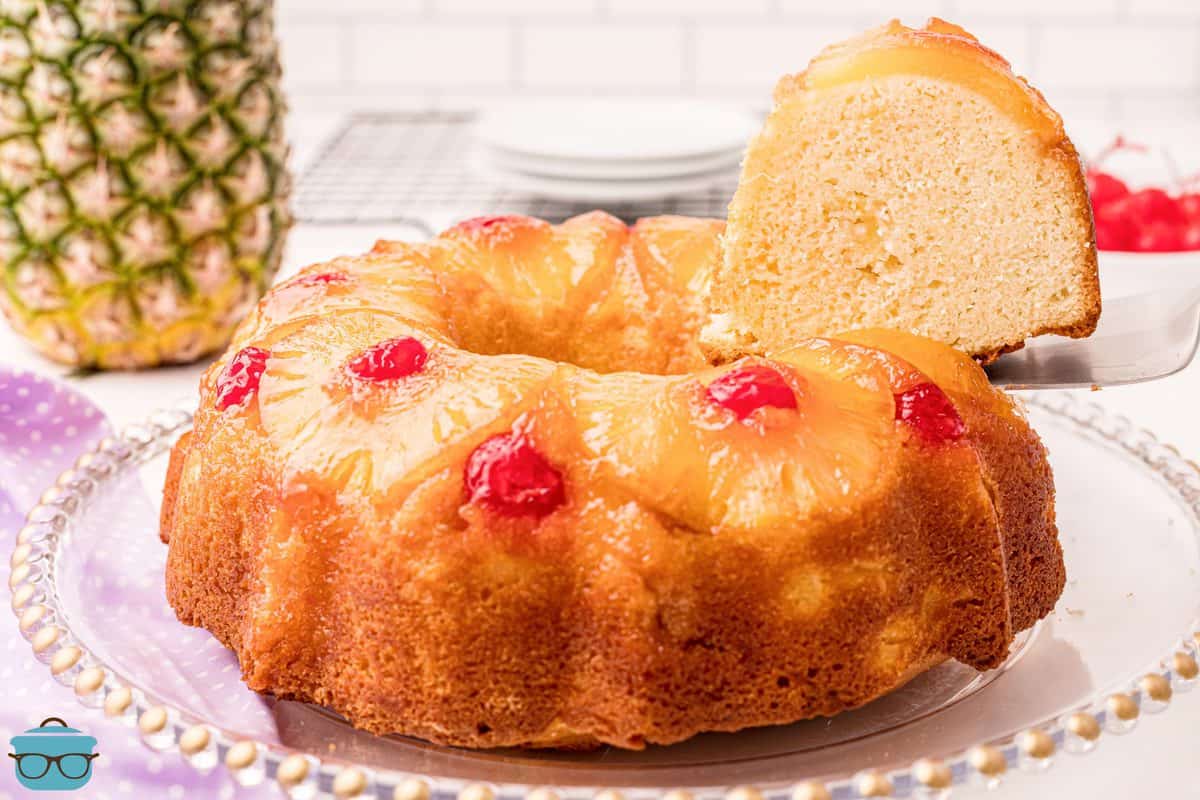 Pineapple Upside Down Cake on platter with slice being taken out of cake.