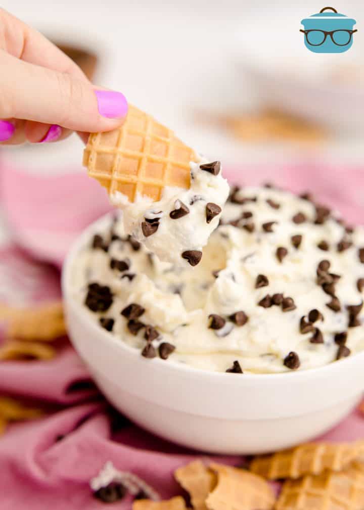 Hand dipping a waffle cone piece into Cannoli Dip
