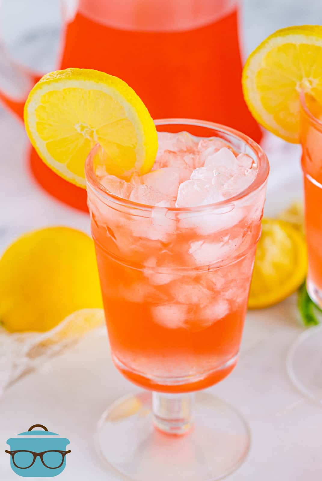 Pink Lemonade Recipe in glass with ice garnished with lemon.