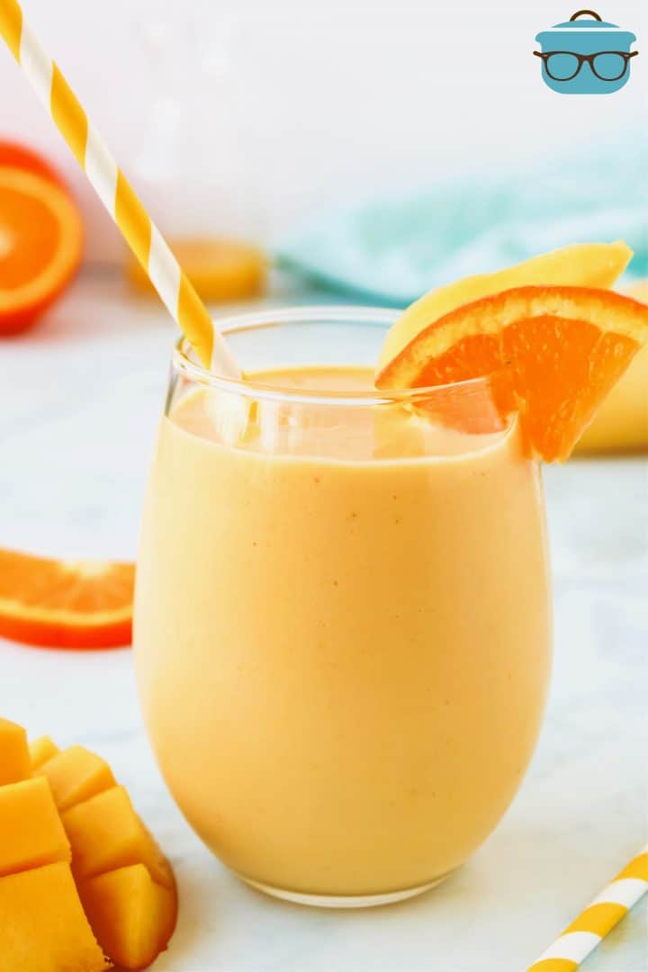 Mango Smoothies close up photo with an orange garnish and inserted orange straw.