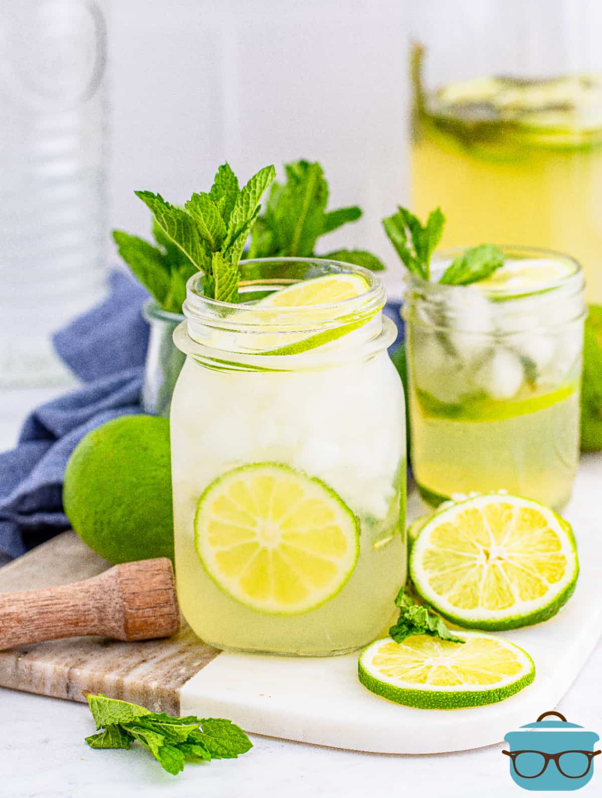 Summer Mojito Recipe in glass with pitcher with mint and lime garnishes.