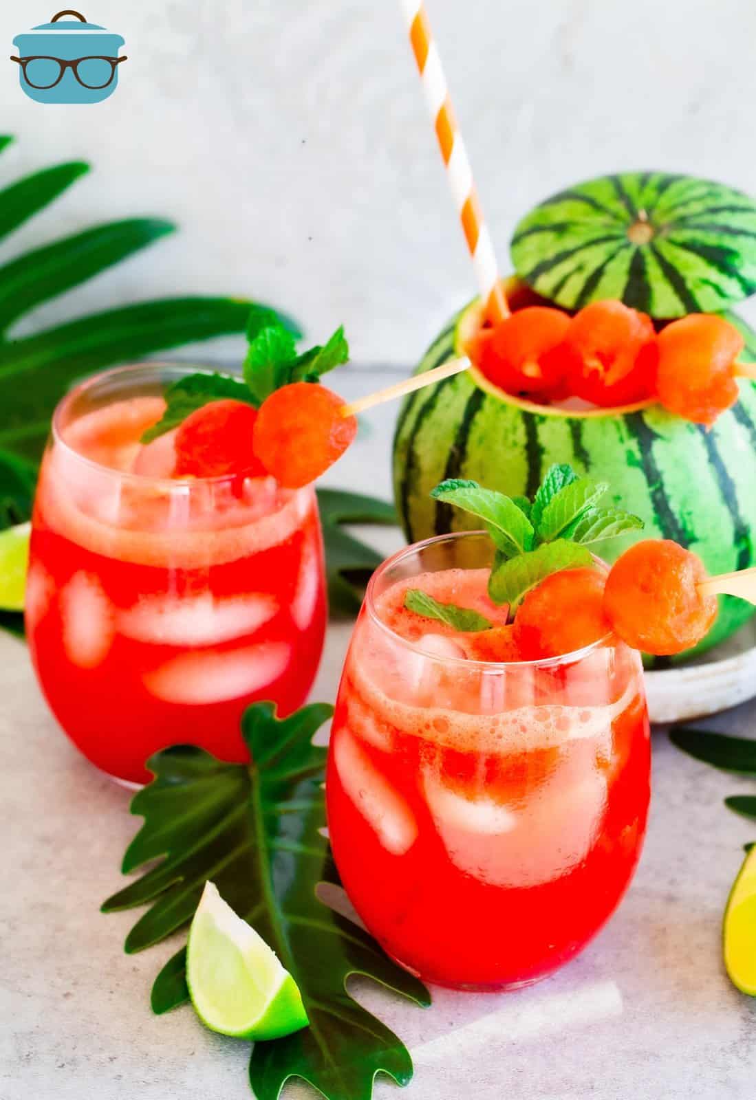 two glasses of watermelon margaritas with a small watermelon in the background