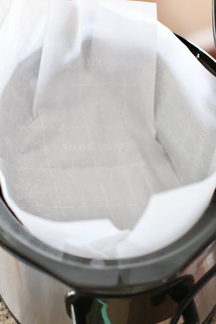 parchment paper lining the bottom of an oval slow cooker