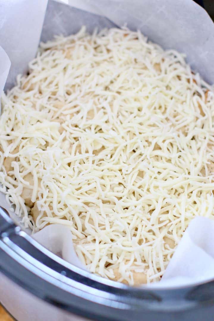 shredded mozzarella cheese on top of cooked biscuits in slow cooker