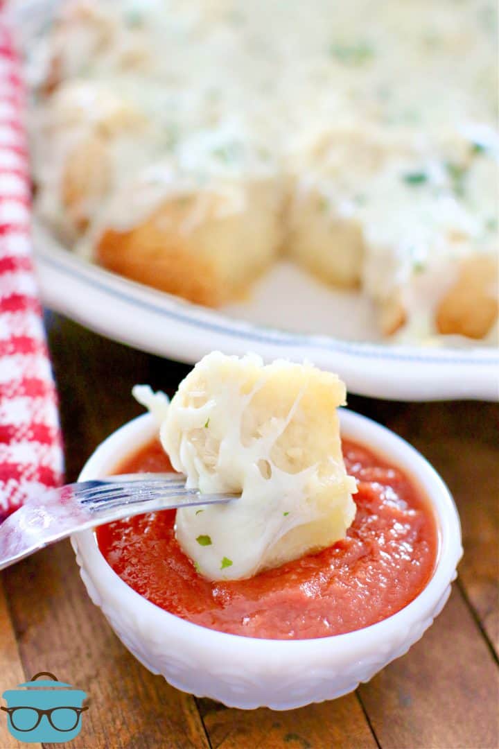 slice of cheese garlic biscuit bread dipped in pizza sauce using a fork