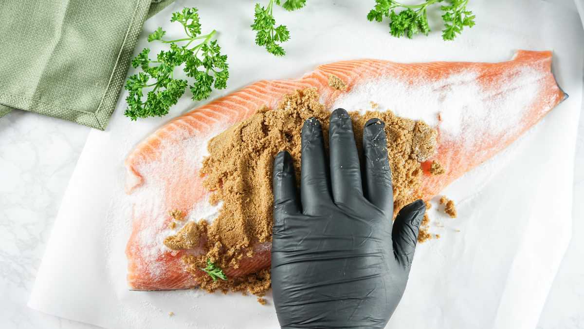 Brown sugar being rubbed over the salt on salmon