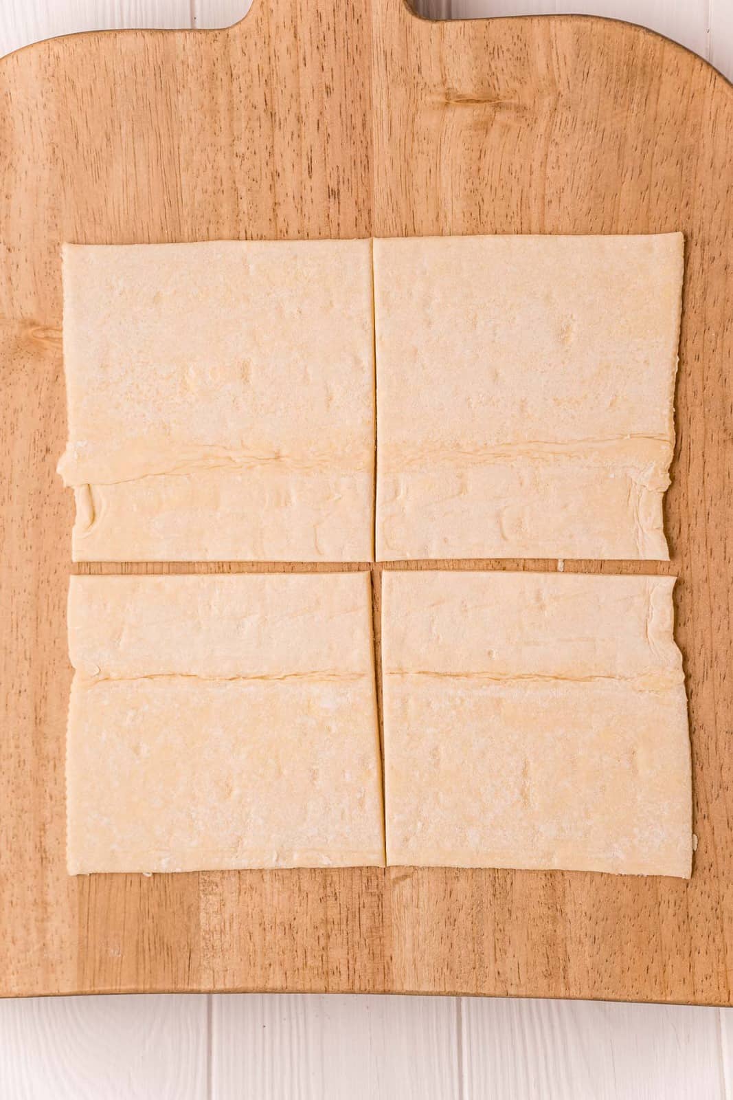 One sheet of puff pastry cut into 4 squares on wooden cutting board