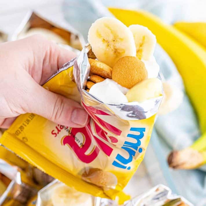 Square photo of hand holding bag of Walking Banana pudding showing bananas and vanilla wafers