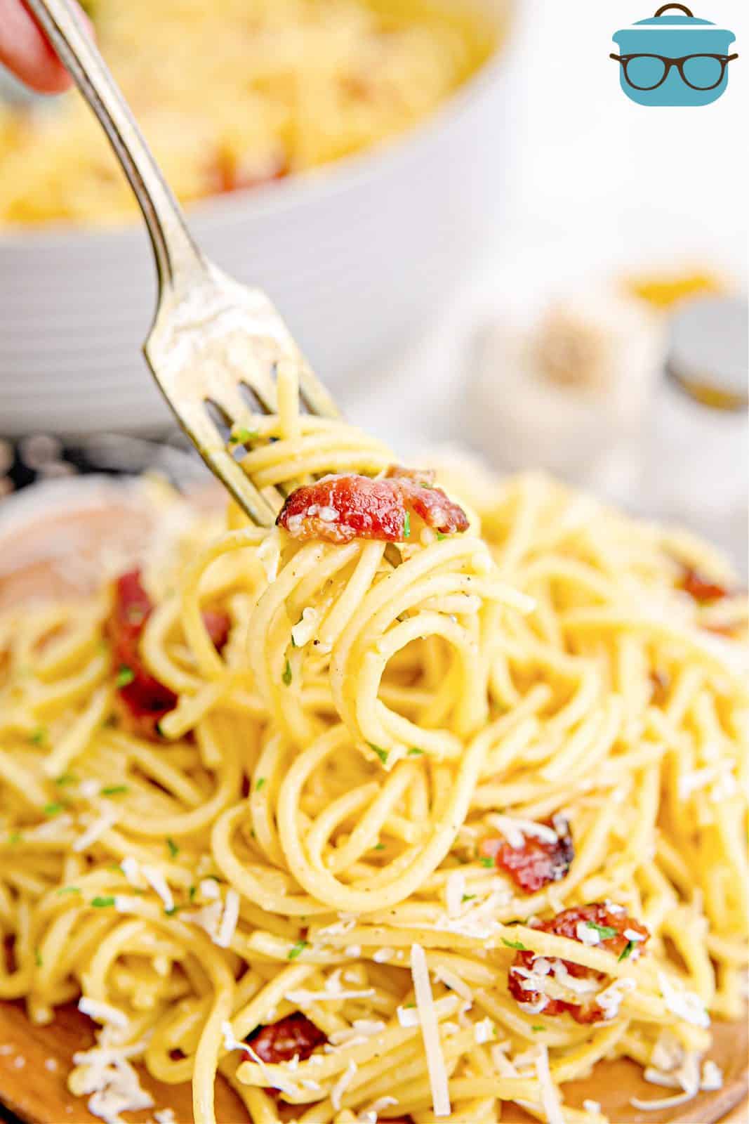 Fork holding up some Bacon Spaghetti Carbonara over a plate.