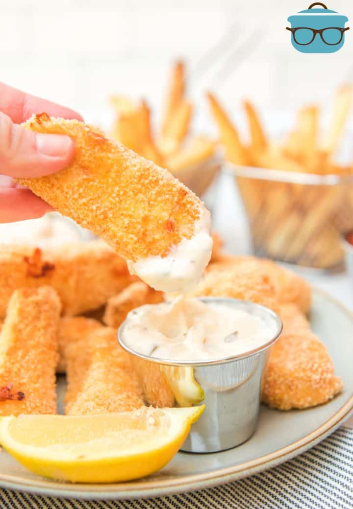 Hand holding up on Air Fryer Homemade Fish Stick after being dipped in sauce