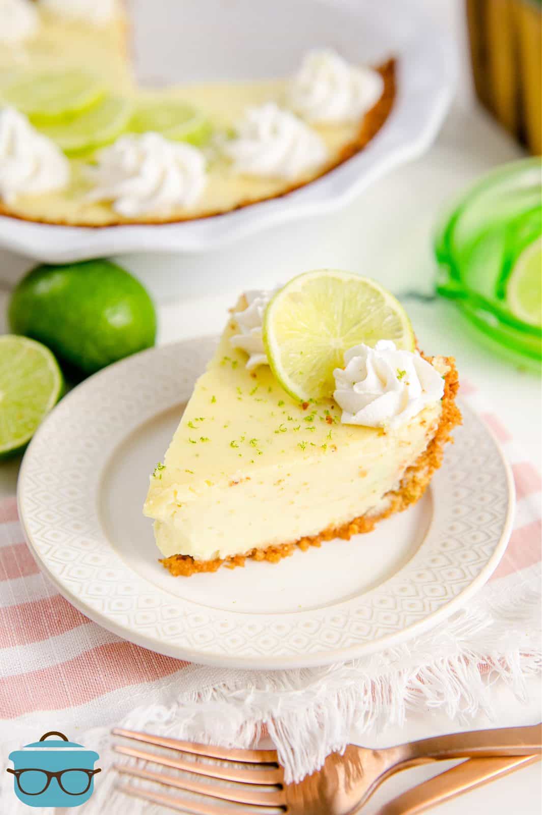 Homemade Key Lime Pie on white plate topped with whipped cream and lime slice