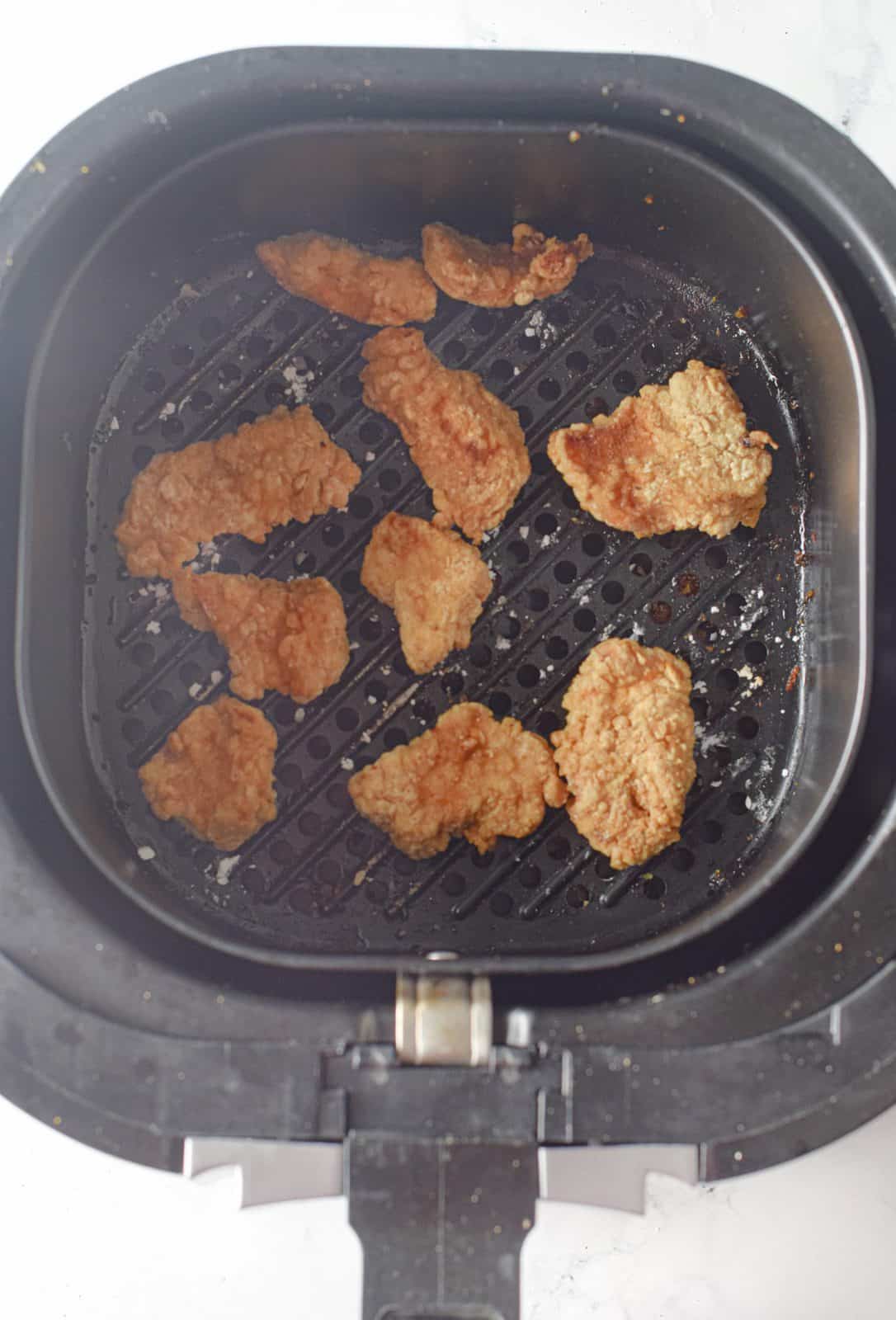 cooked chicken pieces shown in the basket of the air fryer. 