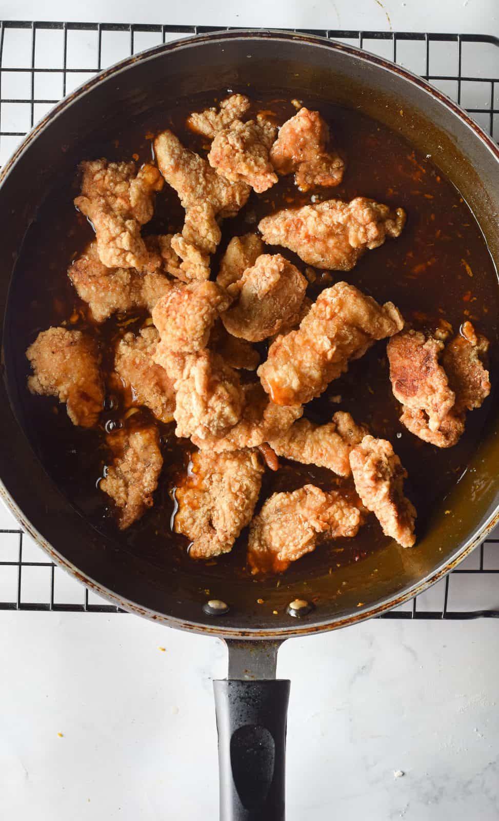 cooked chicken pieces added to orange sauce in a large skillet.