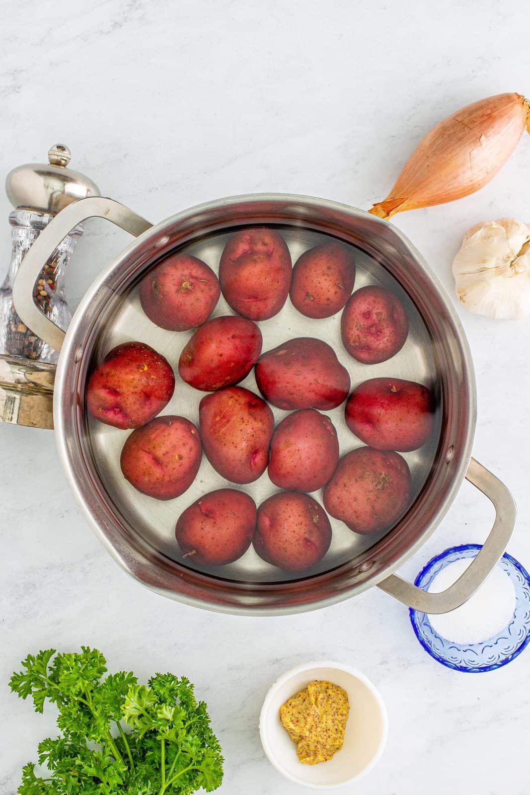 Red potatoes in water in pan.