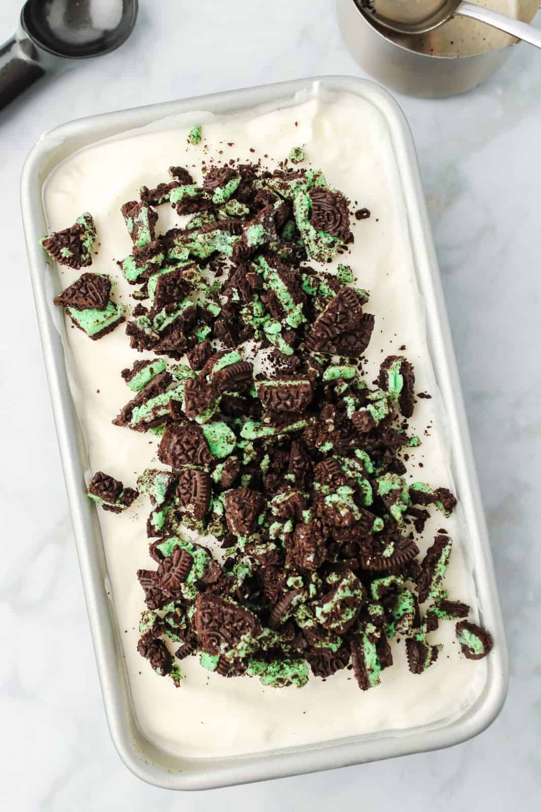 Mint cookies added to ice cream mixture in loaf pan