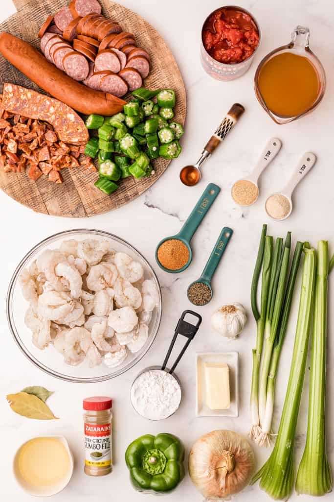Ingredients needed: butter, canola oil, all-purpose flour, sweet onion, green bell pepper, celery ribs, garlic, bay leaves, fire roasted tomatoes, seafood stock, pepper, salt, creole seasoning, andouille sausage, smoked sausage, okra, shrimp and crab boil, shrimp, green onions and gumbo file