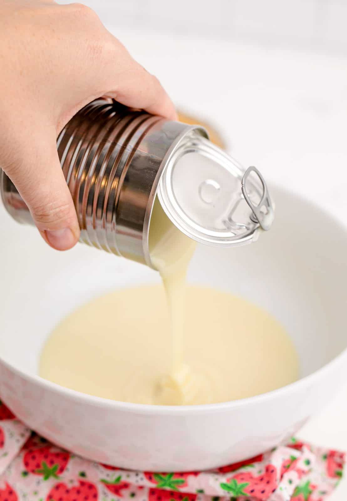 Sweetened condensed milk being poured into a bowl.