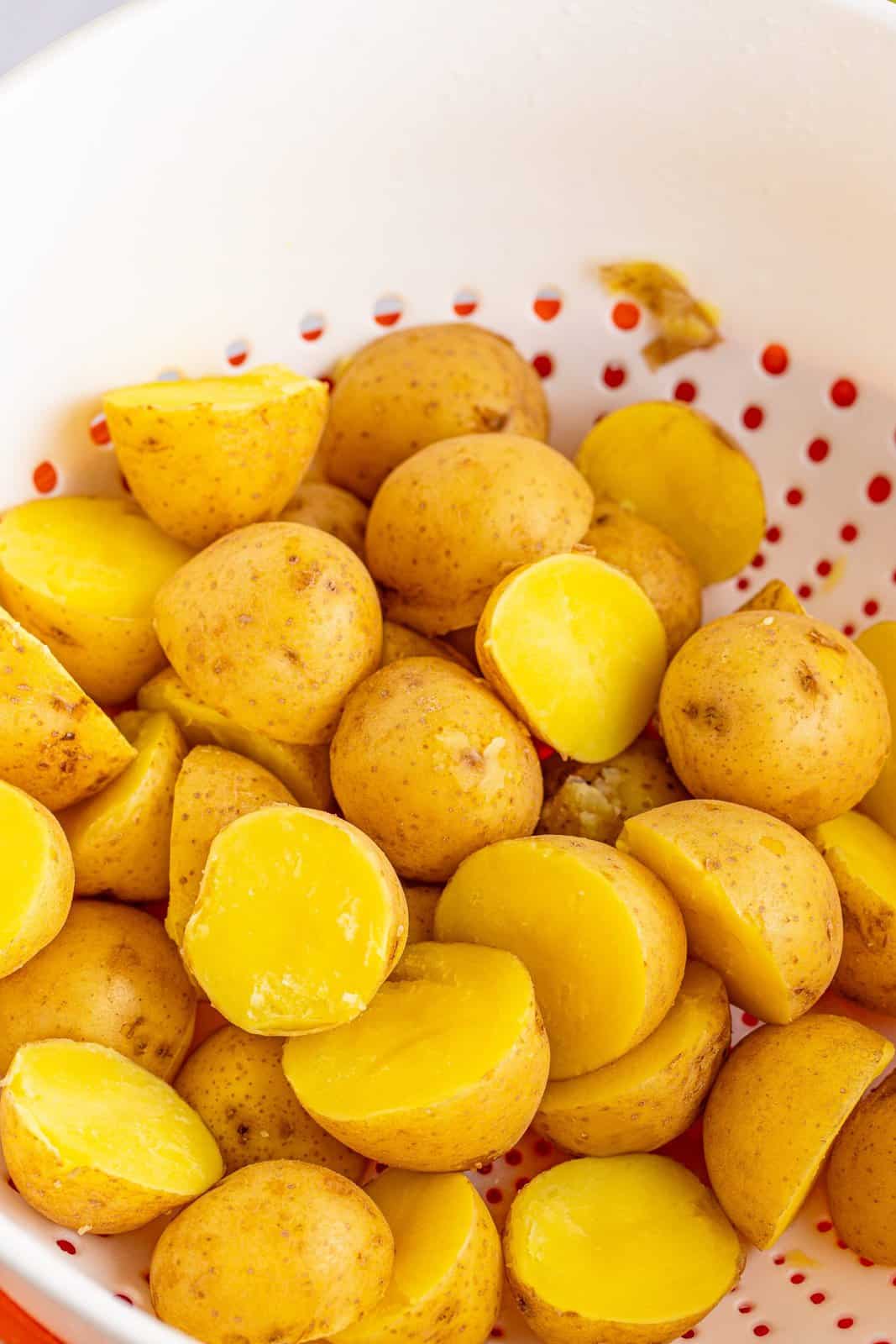cooked and drained baby gold potatoes in a white colander.