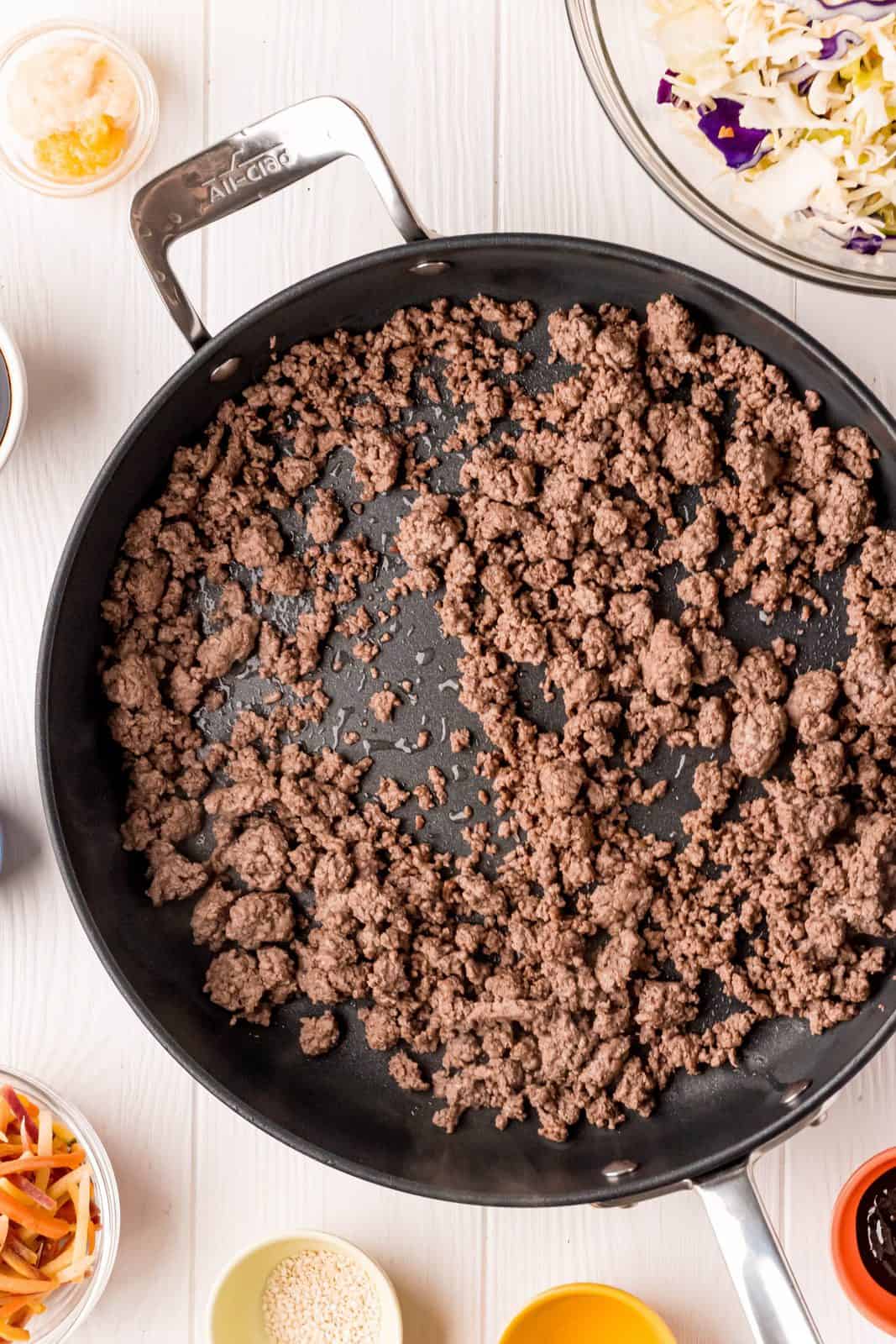 Ground beef being browned and crumbled in a large skillet.